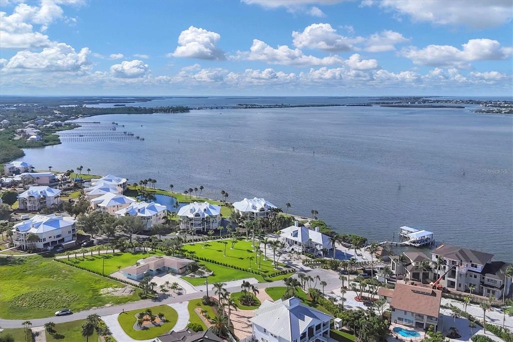 An aerial view shows waterfront houses with white roofs along a bay under a cloudy sky — 550 GASPAR DRIVE, PLACIDA, FL