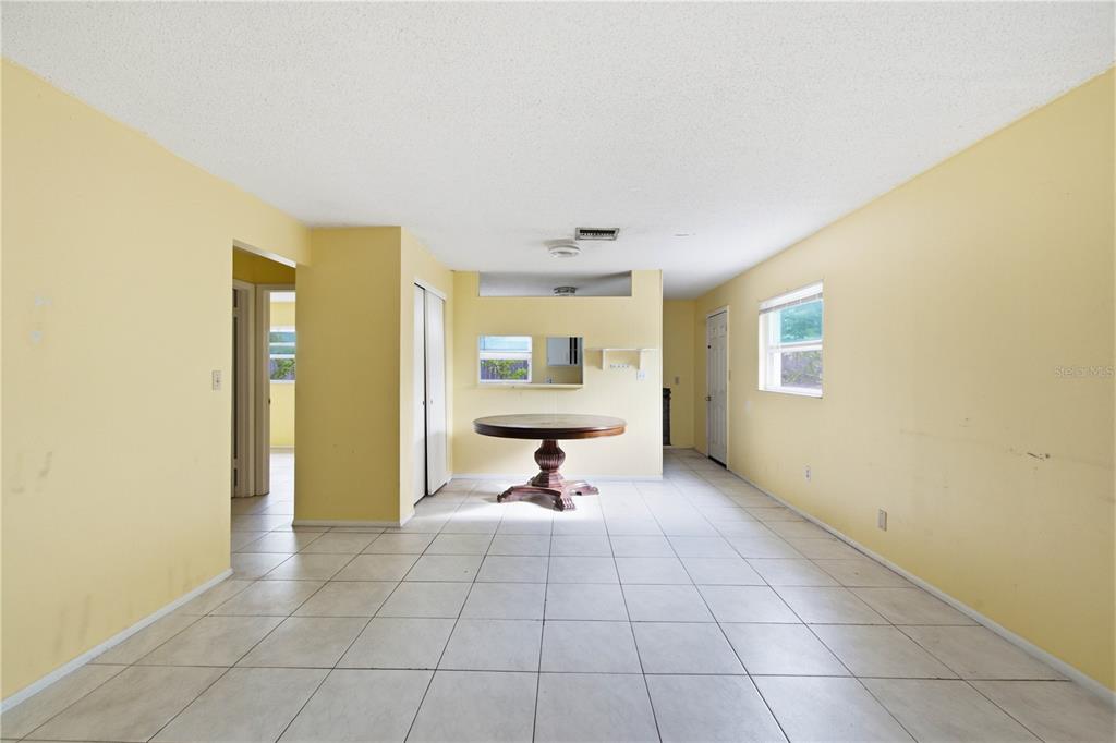 A dining area with yellow walls, white tile flooring, and a round wooden table — 1615 PALM WAY, LARGO, FL