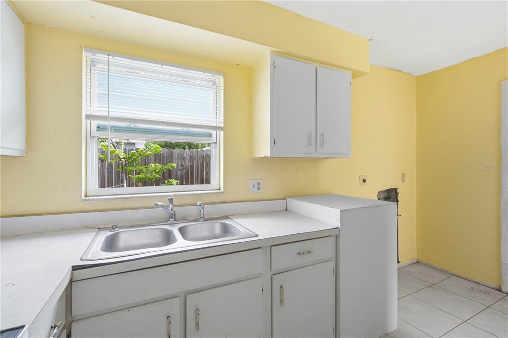 A kitchen with yellow walls, white cabinets, a double-basin sink, and a window — 1615 PALM WAY, LARGO, FL