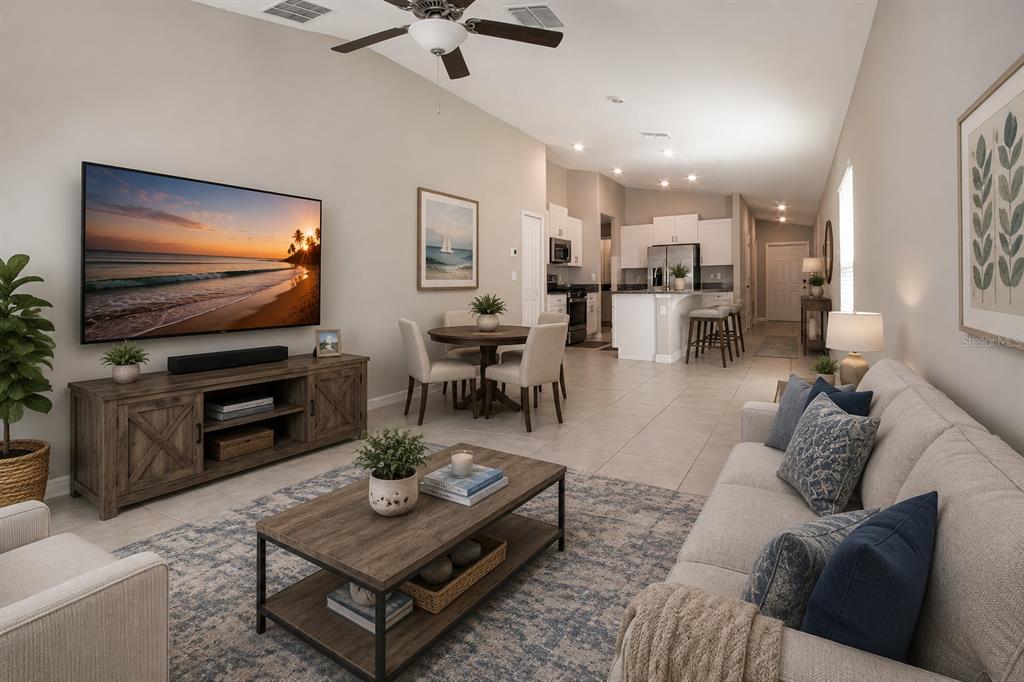 A living room with a television, coffee table, and sofa opens into a kitchen area — 9437 LEMON DROP LOOP, SUN CITY CENTER, FL