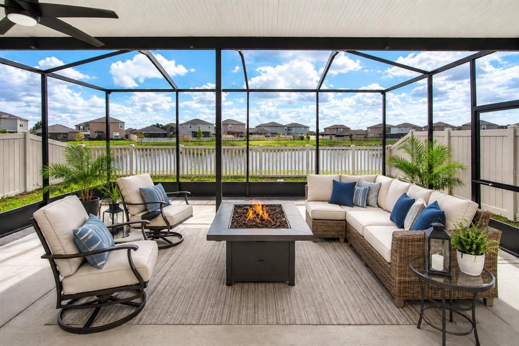 A screened-in patio features a fire pit, outdoor seating, and a view of a pond — 9437 LEMON DROP LOOP, SUN CITY CENTER, FL