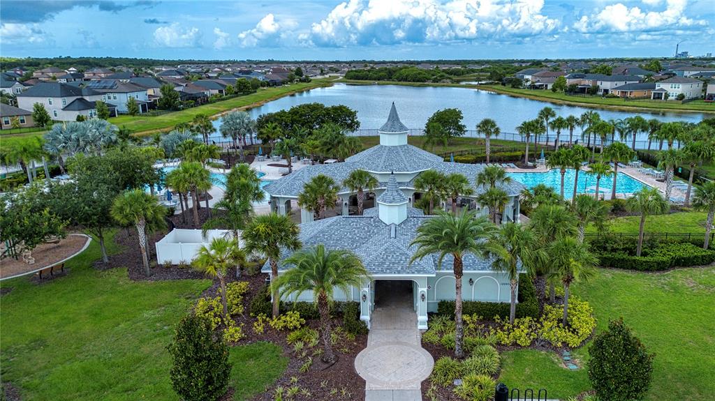 An aerial view shows a community clubhouse with a pool and lake in the background — 9437 LEMON DROP LOOP, SUN CITY CENTER, FL