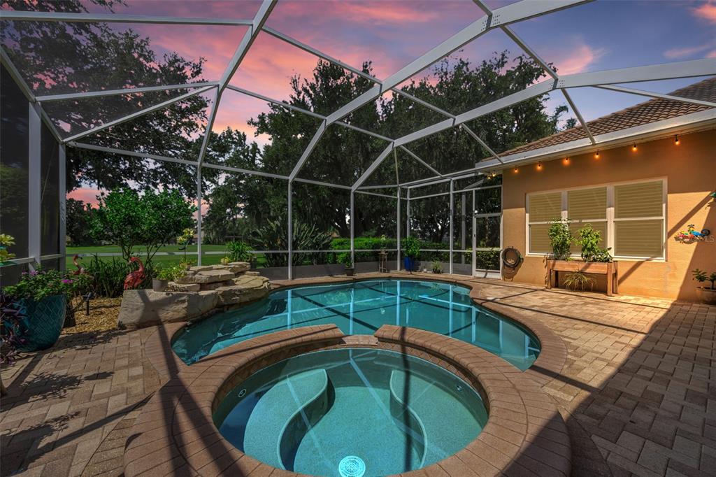 A screened-in patio features a swimming pool, a circular hot tub, and stone pavers — 1453 EL PARDO DRIVE, TRINITY, FL