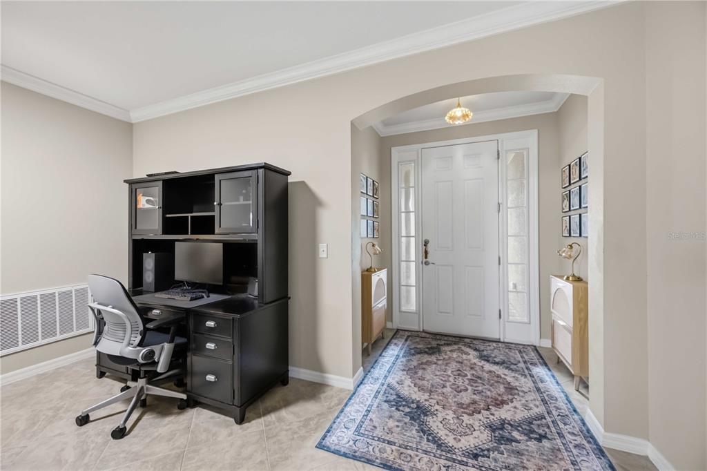 A home office area sits beside an entryway featuring a white door and patterned rug — 5516 CARTAGENA DRIVE, SARASOTA, FL