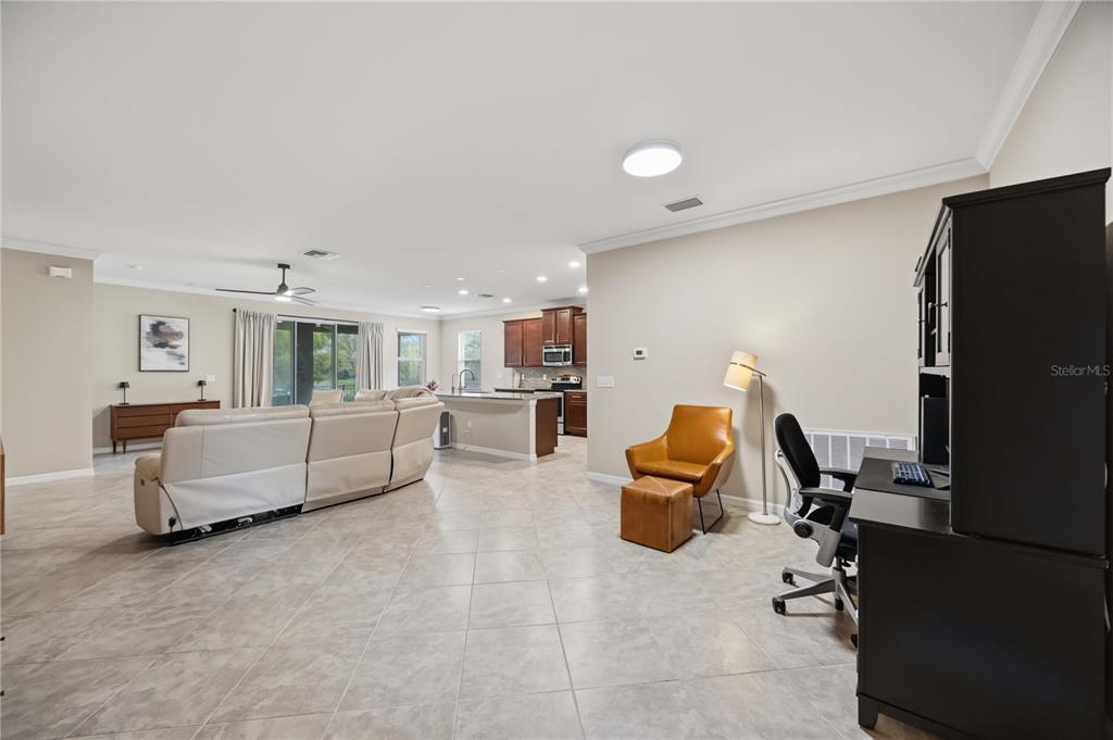 An open-concept living room and kitchen featuring tile flooring, neutral walls, and a leather chair — 5516 CARTAGENA DRIVE, SARASOTA, FL
