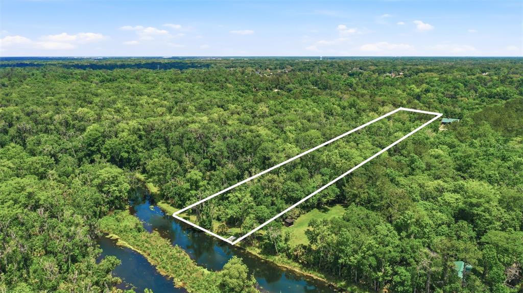 An aerial view shows a rectangular plot of land bordered by a canal and trees — DELK ROAD, LONGWOOD, FL