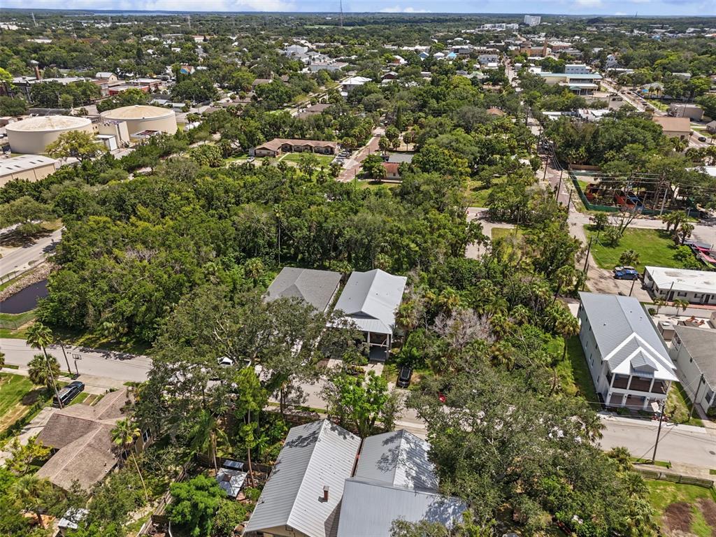 An aerial view shows several houses with metal roofs surrounded by dense trees and vegetation — 170 E SPRUCE STREET, TARPON SPRINGS, FL