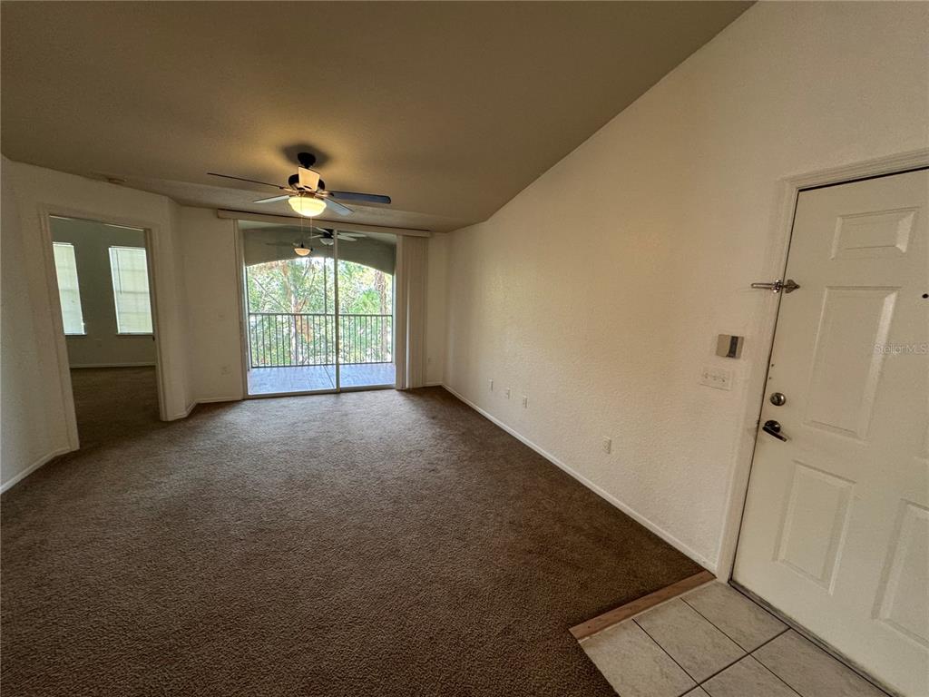A living room with brown carpet, a ceiling fan, and a sliding door to a balcony — 3325 S KIRKMAN ROAD UNIT 438, ORLANDO, FL