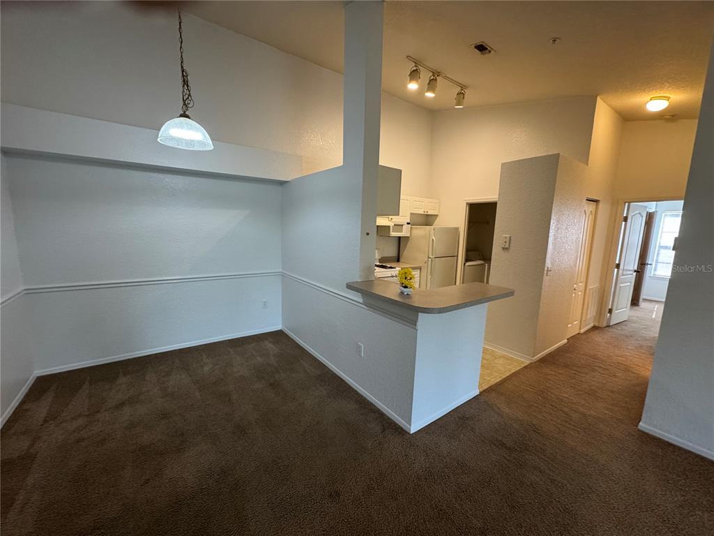 A dining area with carpeted floors leads to a kitchen with a breakfast bar — 3325 S KIRKMAN ROAD UNIT 438, ORLANDO, FL
