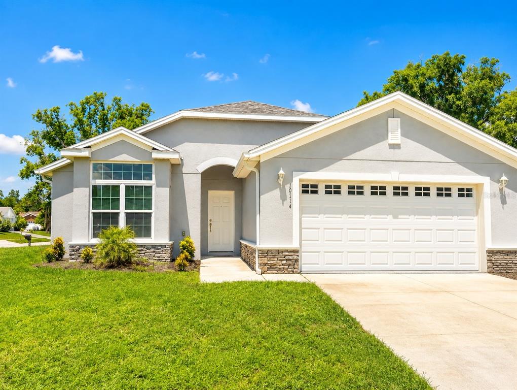 A single-story house with a gray stucco exterior, stone accents, and a two-car garage — 10114 BRIAR CIRCLE, HUDSON, FL