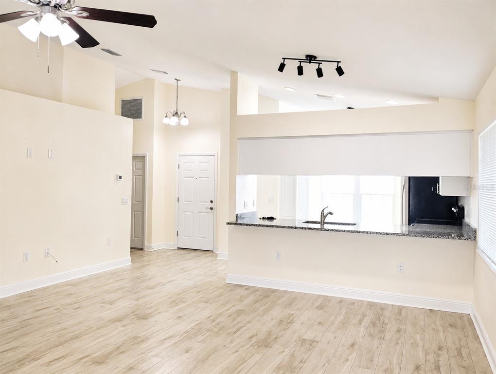 An open-concept living area features light wood-look flooring, a kitchen pass-through, and vaulted ceilings — 10114 BRIAR CIRCLE, HUDSON, FL
