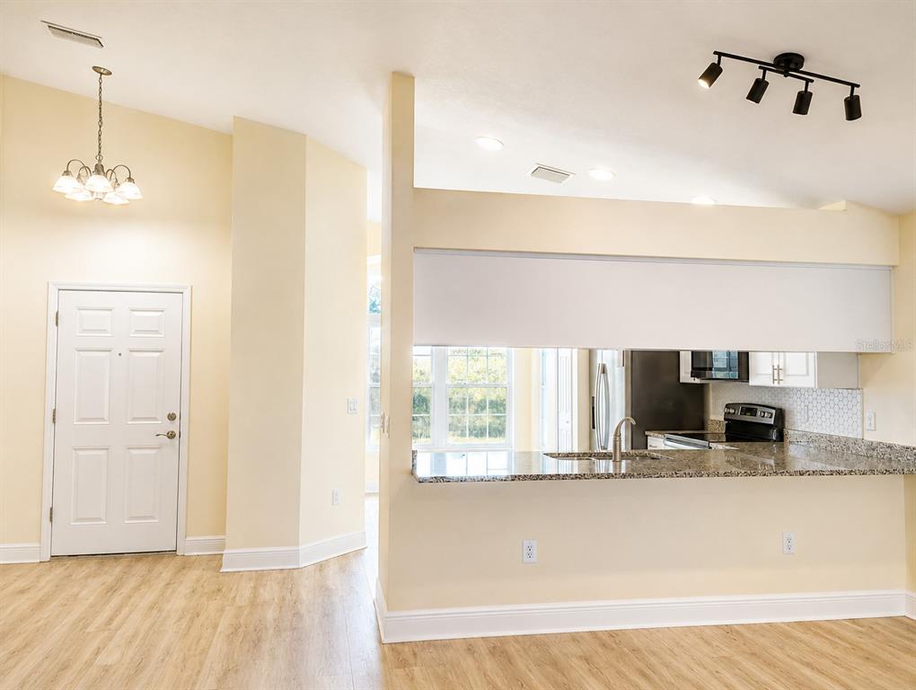 A kitchen with granite countertops is visible through a pass-through window from the living area — 10114 BRIAR CIRCLE, HUDSON, FL