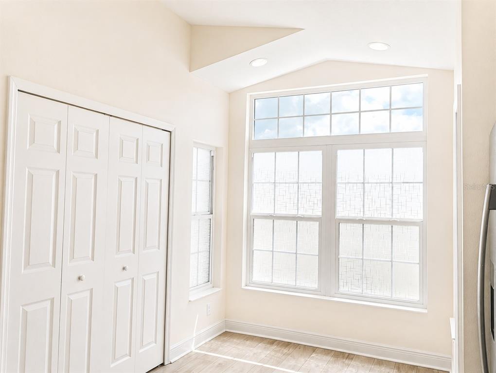 A bright room features white bi-fold closet doors, large windows, and light-colored wood-look flooring — 10114 BRIAR CIRCLE, HUDSON, FL
