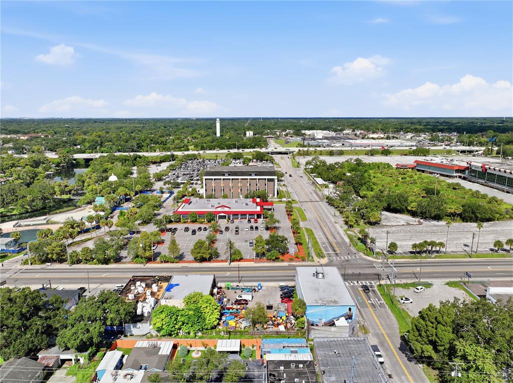 An aerial view shows a commercial area with buildings, parking lots, and surrounding greenery — 8145 N NEBRASKA AVE, TAMPA, FL