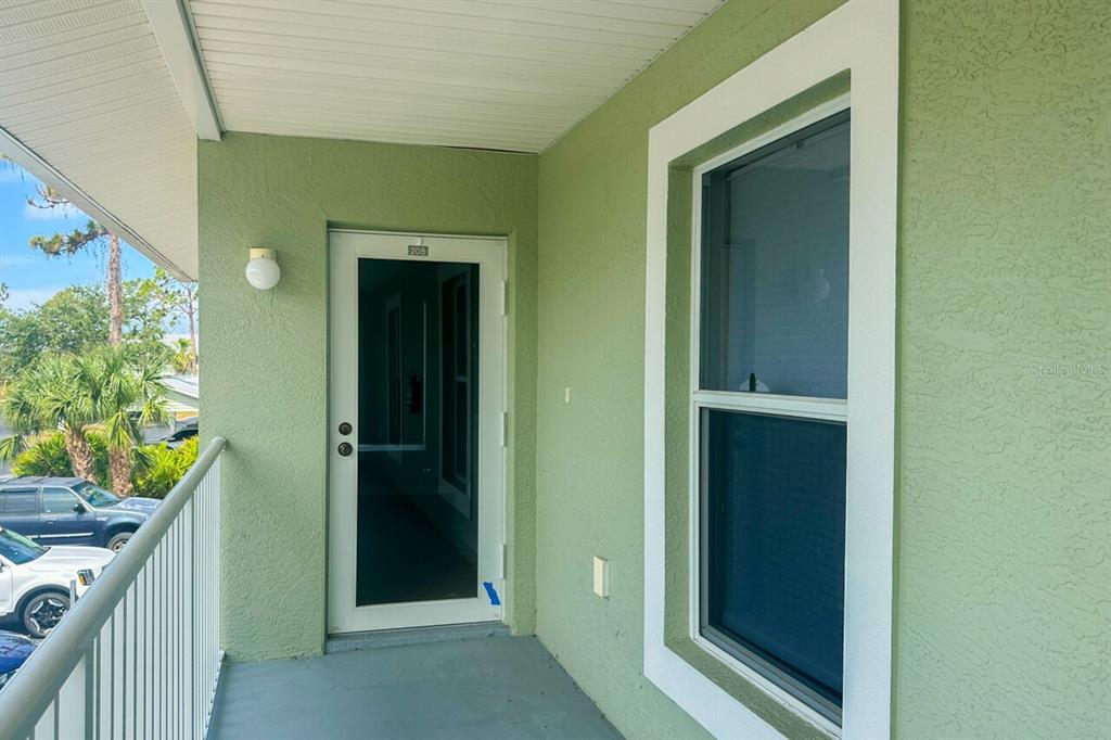 A green exterior wall features a white-framed door labeled 206 and a single window — 8100 MEMORY LANE UNIT 208, ROTONDA WEST, FL