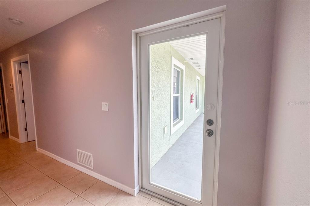A glass door opens from a tiled hallway to an exterior covered walkway — 8100 MEMORY LANE UNIT 208, ROTONDA WEST, FL