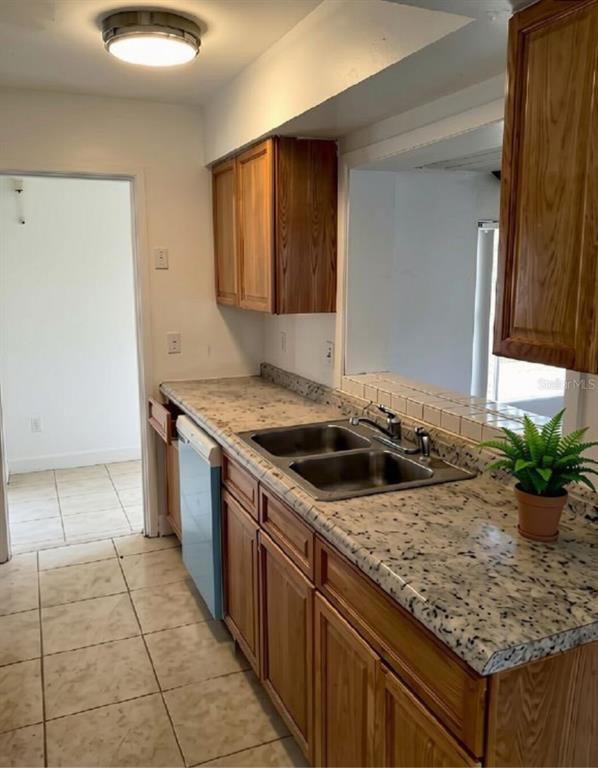 A kitchen features wood cabinets, a double-basin sink, and speckled laminate countertops — 1001 BAY BREEZE TERRACE, LARGO, FL