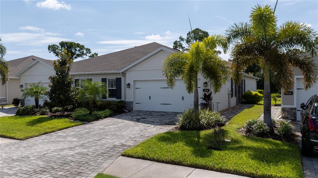 A single-story house with a white garage, paved driveway, and palm trees in the front yard — 1820 W PALMS DRIVE, PORT CHARLOTTE, FL