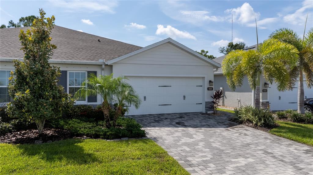 A single-story house exterior features a white garage, a paved driveway, and palm trees — 1820 W PALMS DRIVE, PORT CHARLOTTE, FL