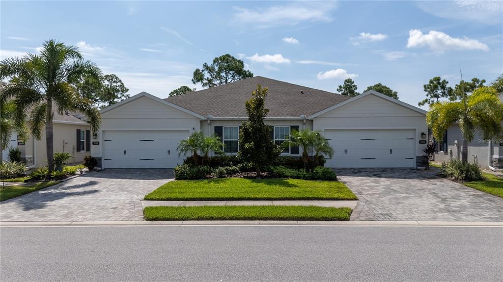 A duplex home with two garages, a paved driveway, and a central landscaped lawn — 1820 W PALMS DRIVE, PORT CHARLOTTE, FL