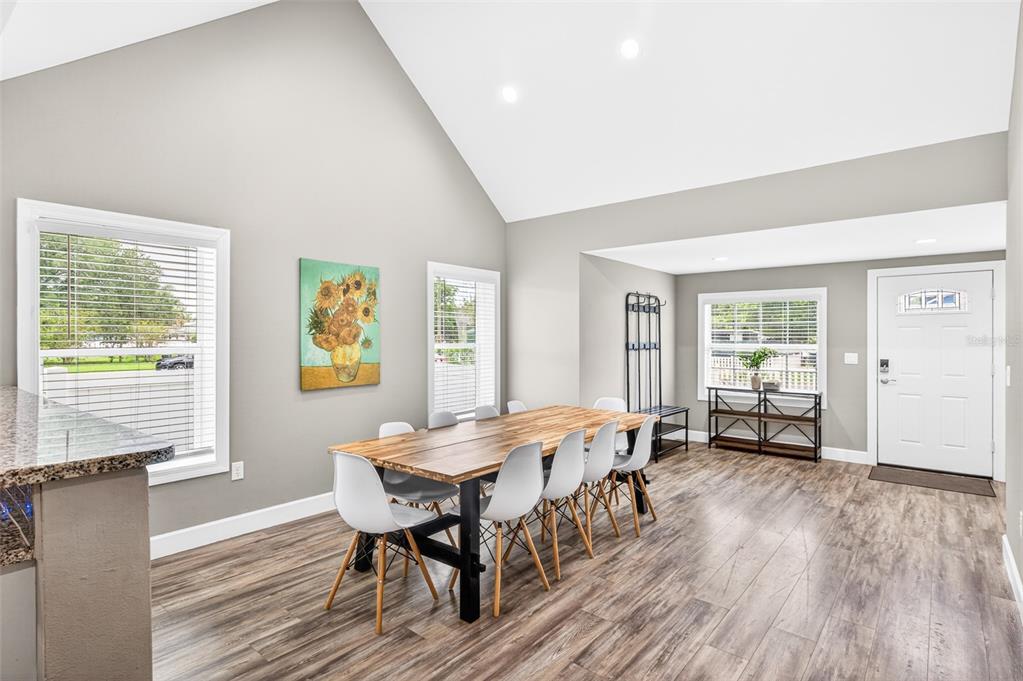A dining room with a wooden table, white chairs, vaulted ceilings, and wood-look flooring — 420 E CYPRESS STREET, WINTER GARDEN, FL