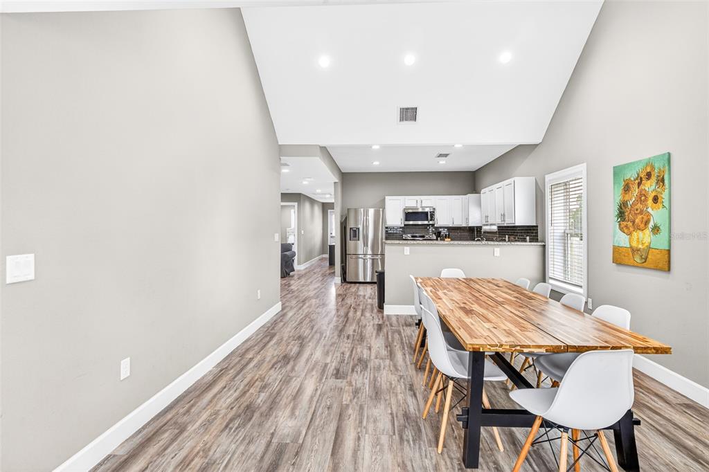 A dining area with a wood table and white chairs sits before an open kitchen — 420 E CYPRESS STREET, WINTER GARDEN, FL