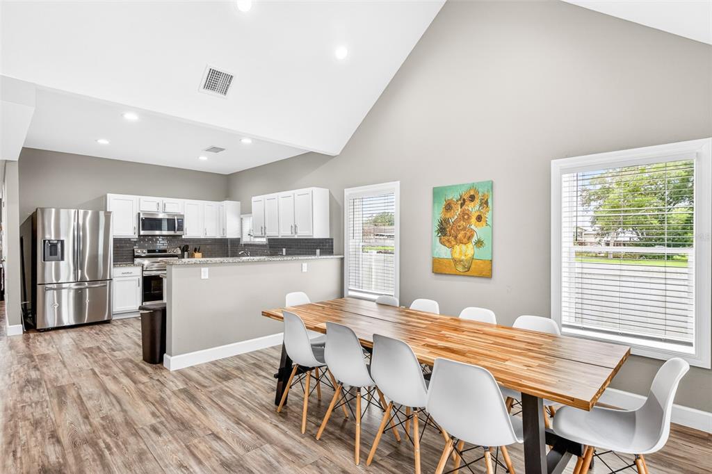 A dining area with a wooden table and white chairs sits beside an open kitchen — 420 E CYPRESS STREET, WINTER GARDEN, FL