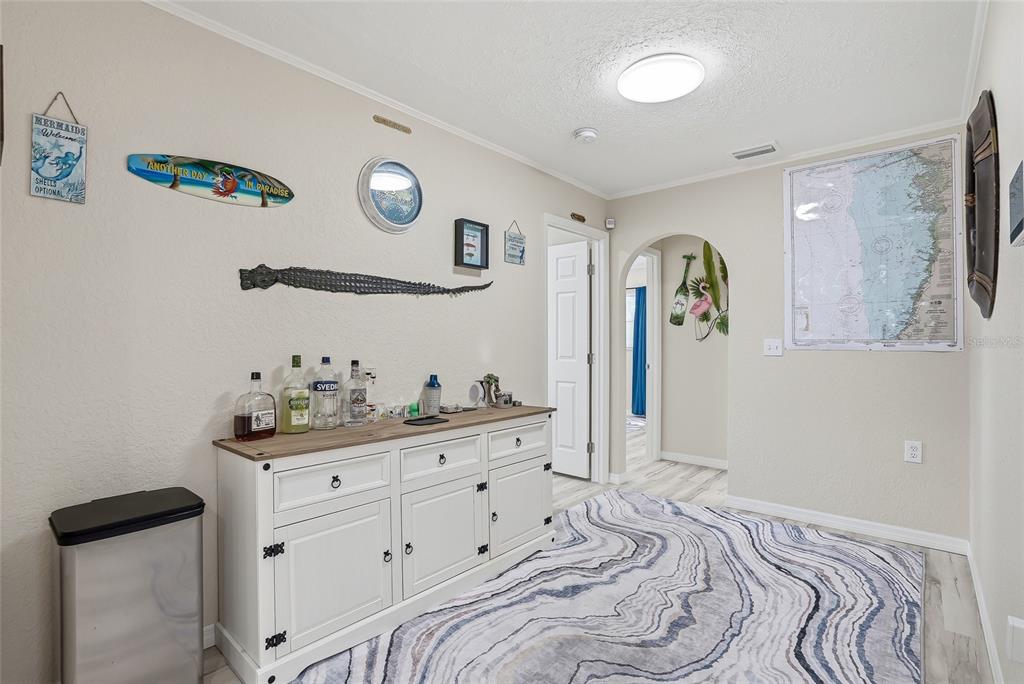 A hallway features a white sideboard bar, a patterned area rug, and coastal wall decor — 3332 GULF WINDS CIRCLE, HERNANDO BEACH, FL