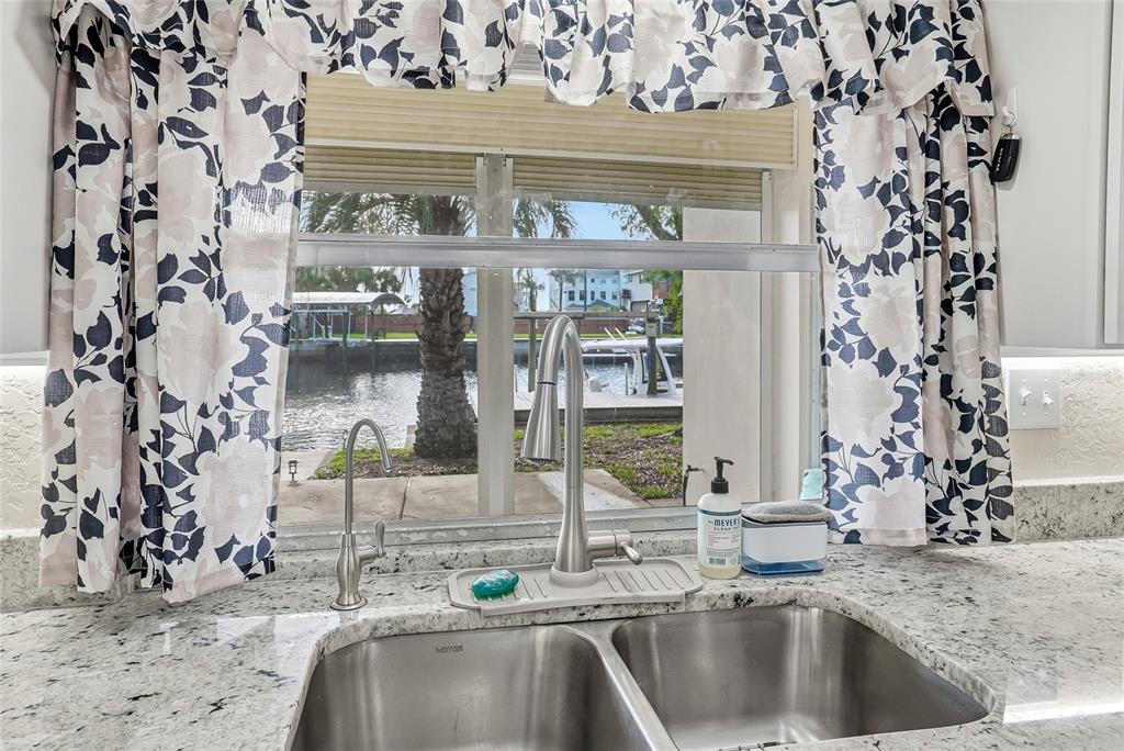 A kitchen sink with a view of a canal through a window with floral curtains — 3332 GULF WINDS CIRCLE, HERNANDO BEACH, FL