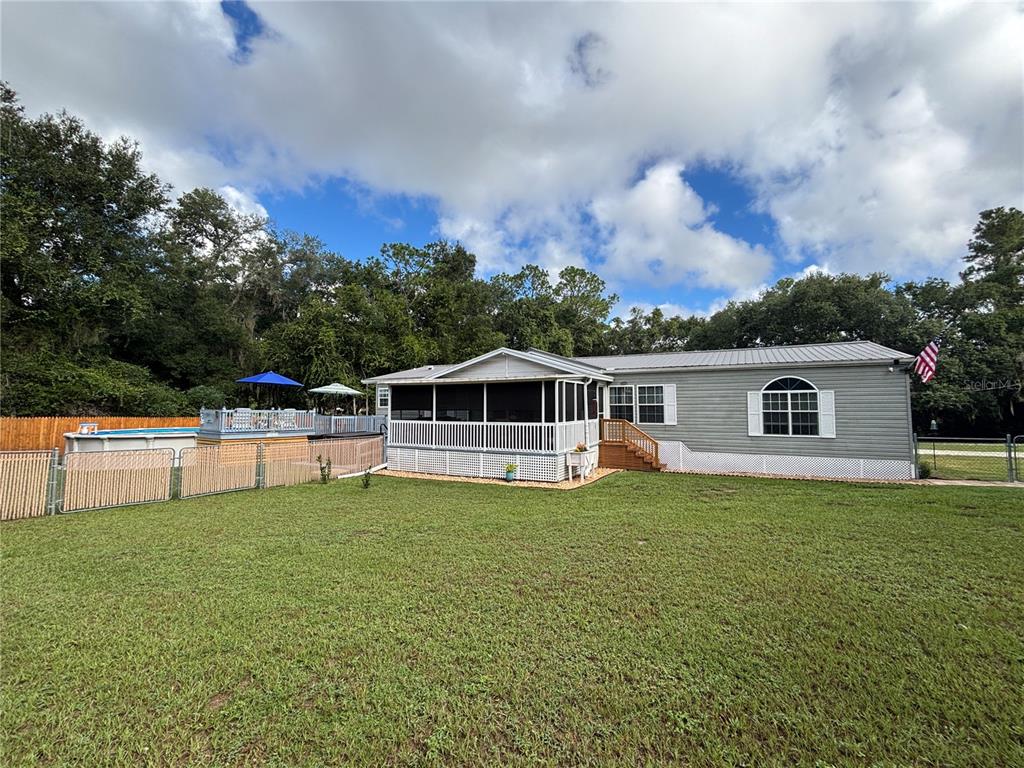 A gray manufactured home features a screened-in porch, an above-ground pool, and a fenced yard — 1762 SE 173RD AVENUE, SILVER SPRINGS, FL