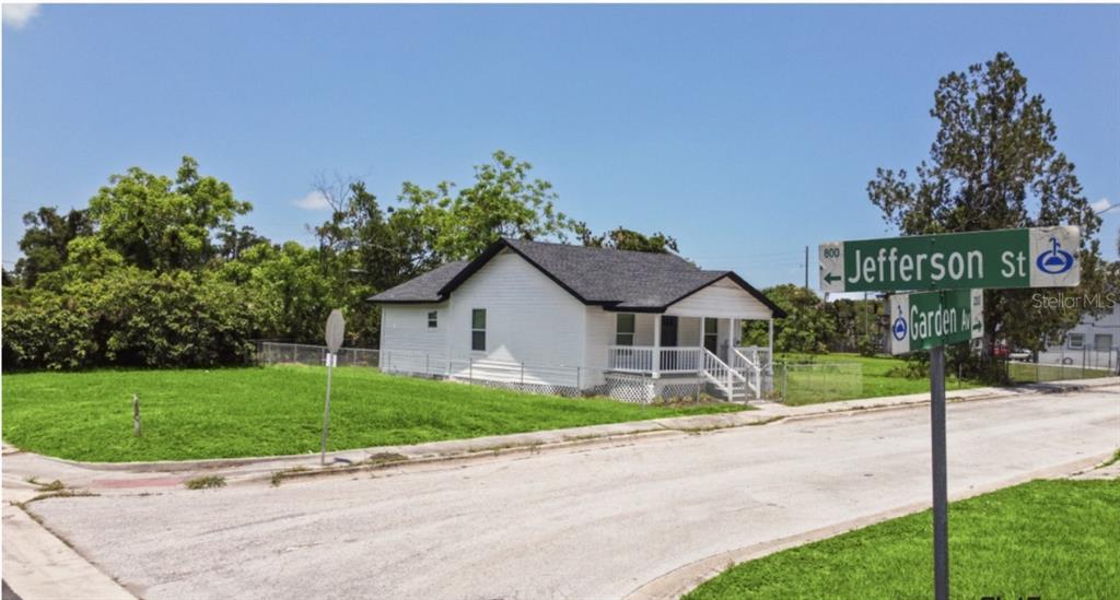 A white house with a dark roof sits on a corner lot at a street intersection — 204 GARDEN AVENUE, ORLANDO, FL