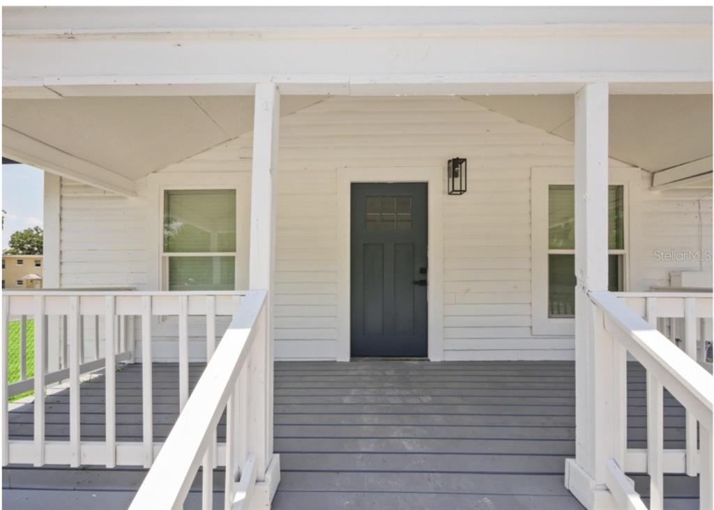 A front porch with white siding, a dark blue door, and gray wooden decking — 204 GARDEN AVENUE, ORLANDO, FL