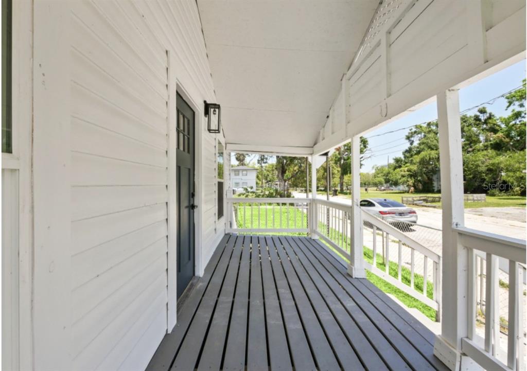 A covered front porch with gray wooden decking, white railings, and a dark entry door — 204 GARDEN AVENUE, ORLANDO, FL