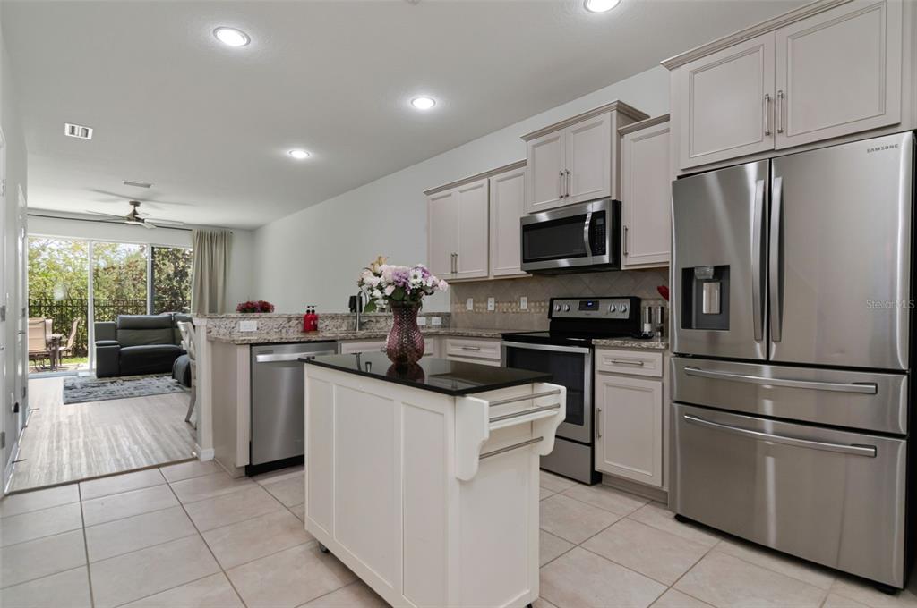 A kitchen with light-colored cabinets, stainless steel appliances, a kitchen island, and tile flooring — 9213 HILLCROFT DRIVE, RIVERVIEW, FL