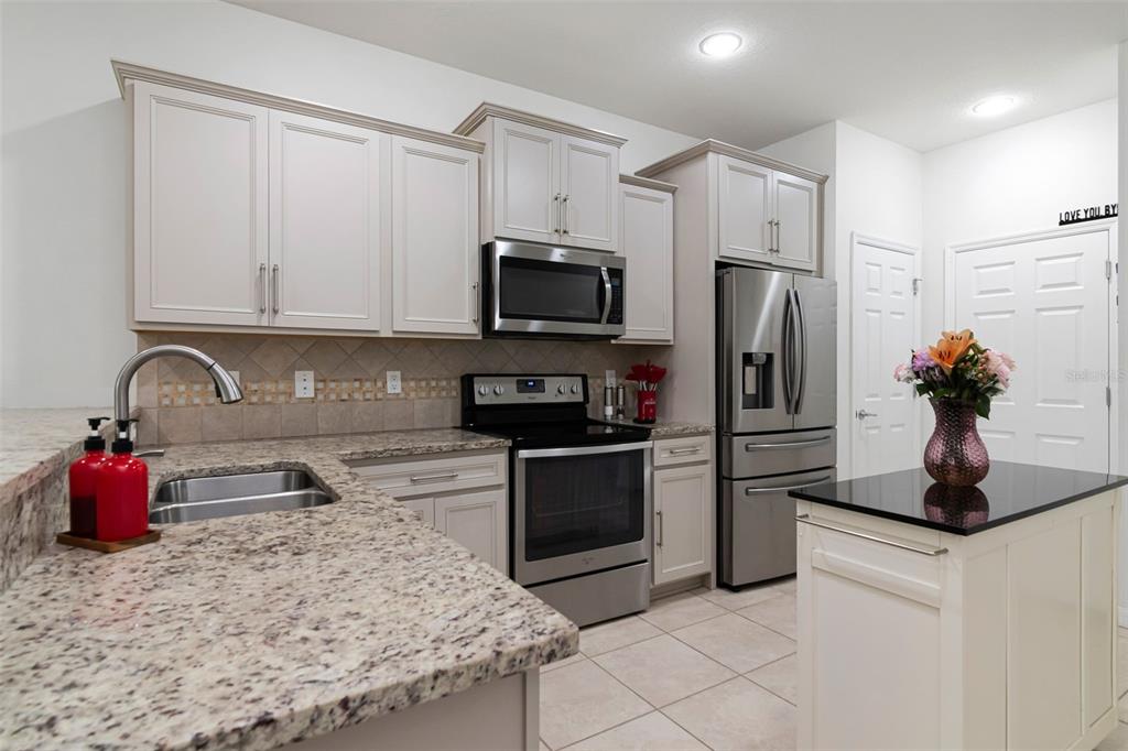 A kitchen features light-colored cabinets, granite countertops, stainless steel appliances, and a small island — 9213 HILLCROFT DRIVE, RIVERVIEW, FL