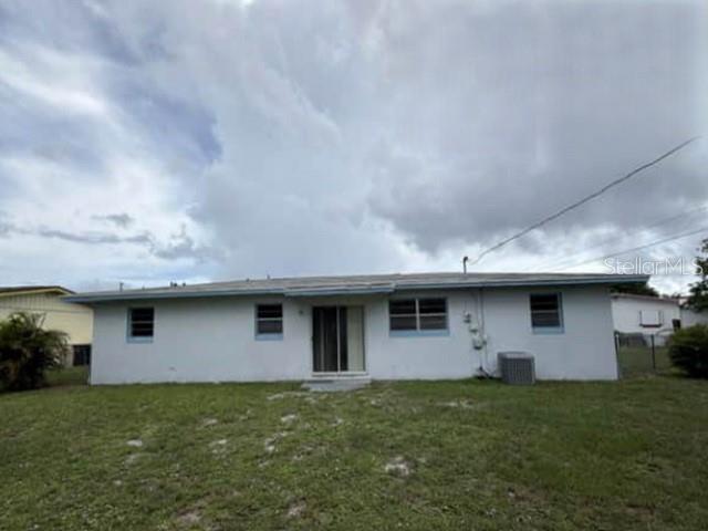 The exterior rear view of a single-story house with a white facade and a grassy yard — 904 SE HALL STREET, STUART, FL