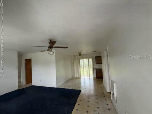 A living room with dark blue carpet, white walls, a ceiling fan, and tiled flooring — 904 SE HALL STREET, STUART, FL