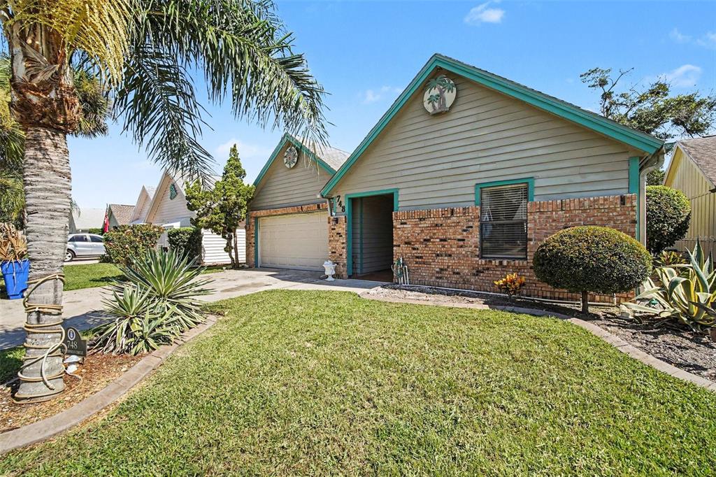 A single-story house with a brick facade, light green siding, and a palm tree in front — 748 PINE SHORES CIRCLE, NEW SMYRNA BEACH, FL