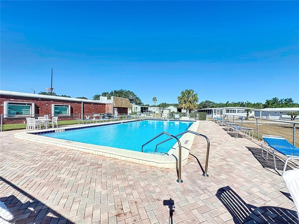 An outdoor swimming pool with a brick paver deck and surrounding lounge chairs — 148 ORANGEWOOD DRIVE, LAKE WALES, FL