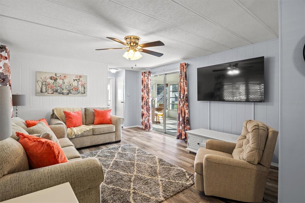 A living room features a sofa, a recliner, a large television, and a ceiling fan — 148 ORANGEWOOD DRIVE, LAKE WALES, FL