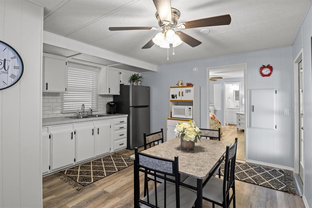 A kitchen and dining area with white cabinets, stainless steel appliances, and a dining table — 148 ORANGEWOOD DRIVE, LAKE WALES, FL