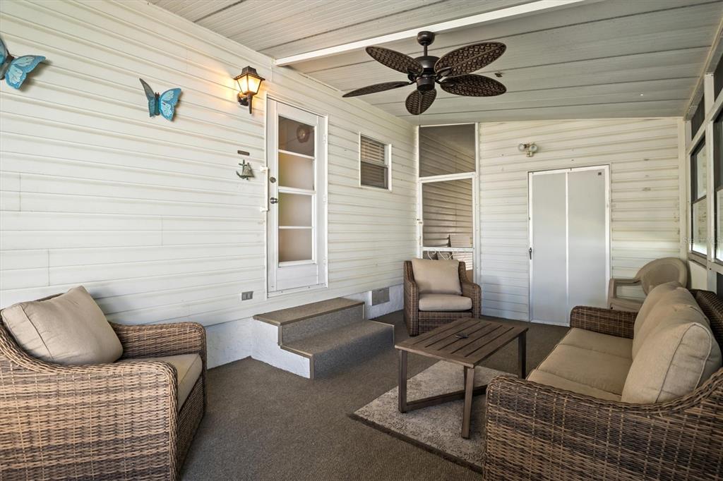 A covered porch features wicker furniture, a ceiling fan, and white horizontal siding — 148 ORANGEWOOD DRIVE, LAKE WALES, FL