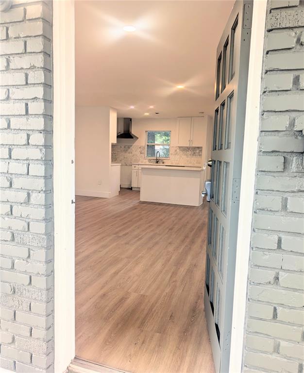 A view through an open door into a kitchen with white cabinets and wood flooring — 3006 E ANDERSON STREET, ORLANDO, FL