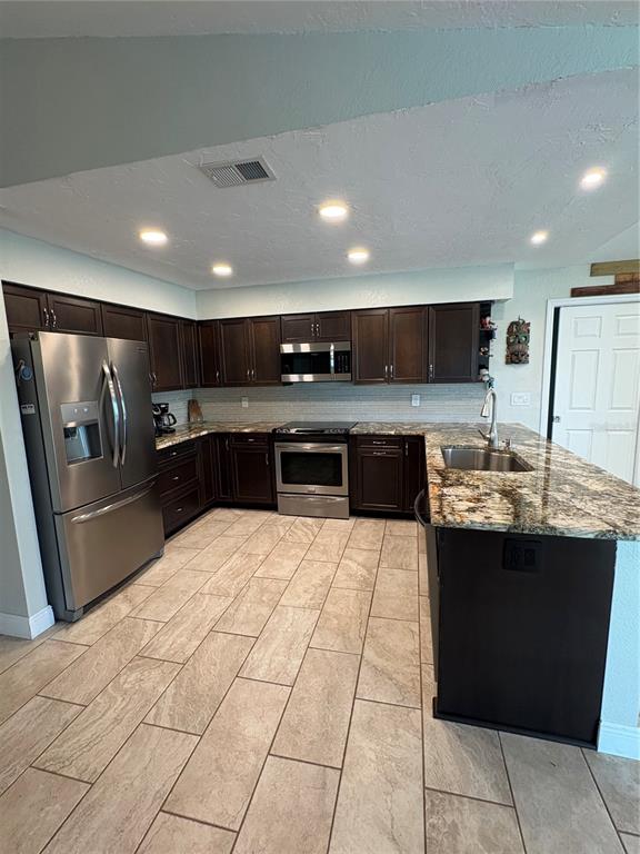A kitchen features dark wood cabinets, stainless steel appliances, granite countertops, and light tile flooring — 5092 KILTY COURT E, BRADENTON, FL