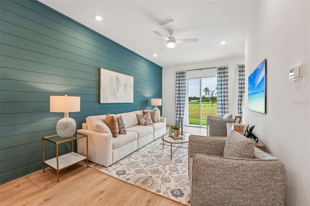 A living room features a teal shiplap accent wall, light-colored sofa, and sliding glass doors — 15016 CATTERICK COURT, JACKSONVILLE, FL