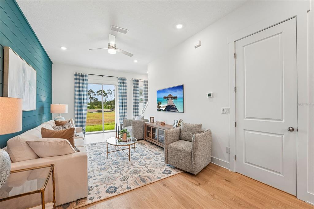 A living room features a blue shiplap accent wall, light wood floors, and sliding glass doors — 15016 CATTERICK COURT, JACKSONVILLE, FL