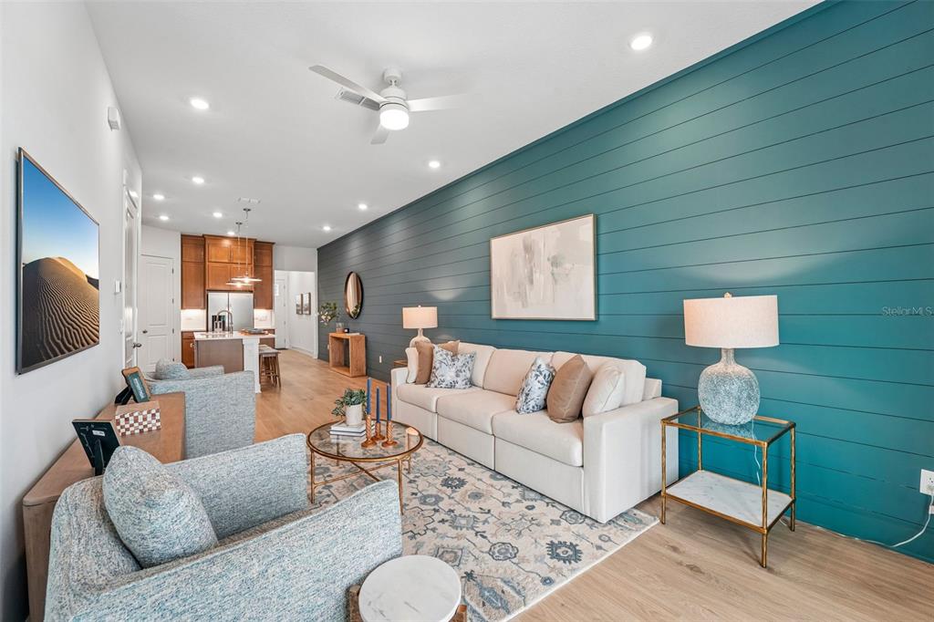 A living room features a teal shiplap accent wall, light wood flooring, and a beige sofa — 15016 CATTERICK COURT, JACKSONVILLE, FL