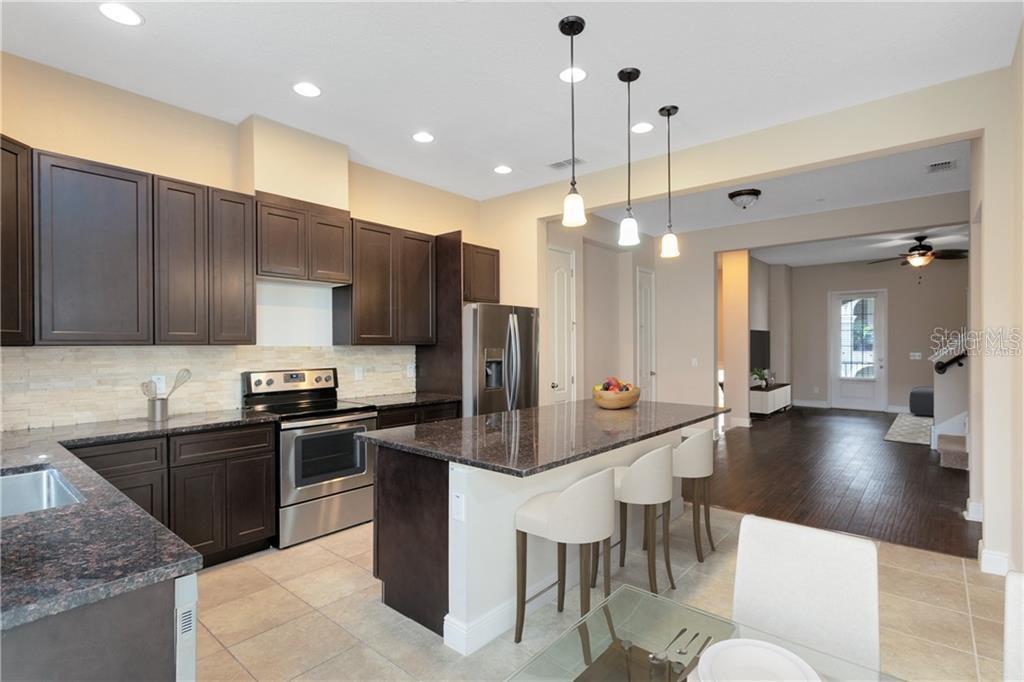 A kitchen with dark wood cabinets, granite countertops, stainless steel appliances, and a center island — 1412 LOBELIA DRIVE, LAKE MARY, FL