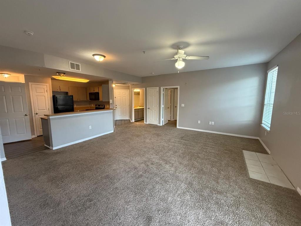 An empty living area features gray walls, brown carpeting, a ceiling fan, and sliding glass doors — 2015 ERVING CIRCLE UNIT 307, OCOEE, FL