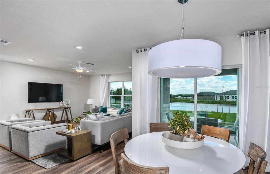 A bright open-concept living and dining area features a view of a pond outside — 10511 SAPPHIRE BREEZE COVE, PARRISH, FL